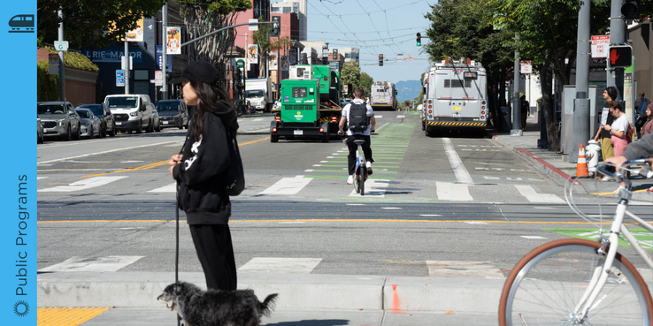 Image of a pedestrian, cyclist, buses, and cars on a busy street in San Francisco